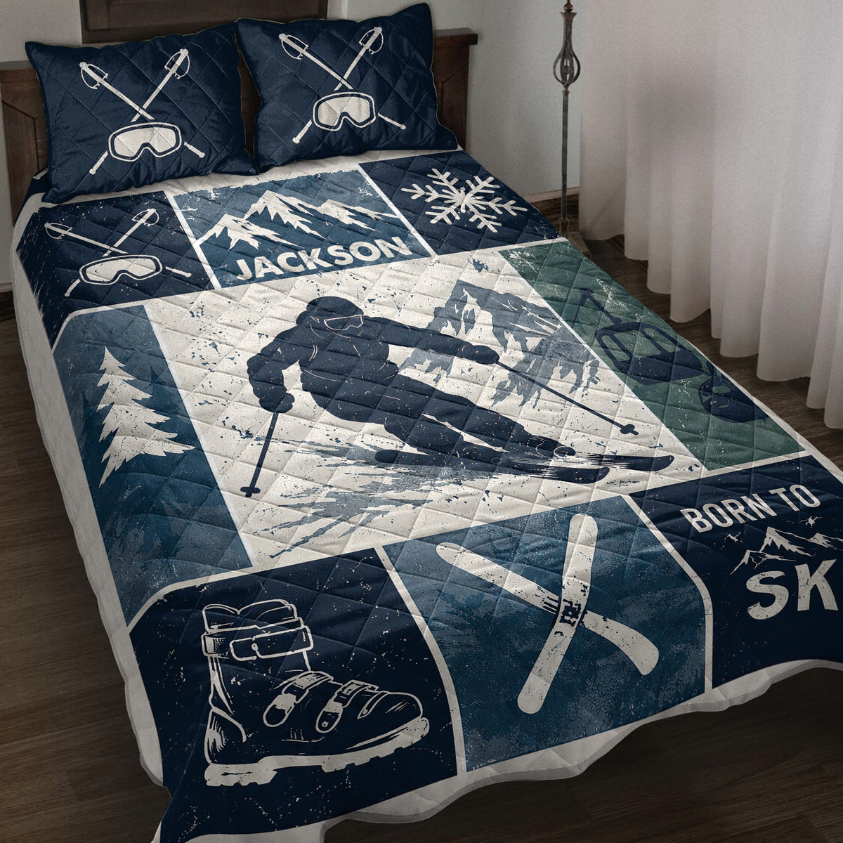 Navy skiing quilt blanket displayed on a bed with mountain artwork, skier imagery, skis, goggles, and snowflakes