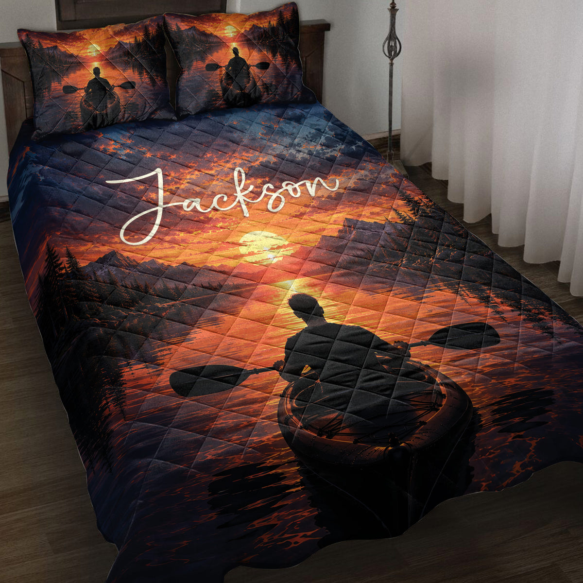 Kayak quilt blanket displayed on a bed with sunset mountain lake artwork and paddler silhouettes