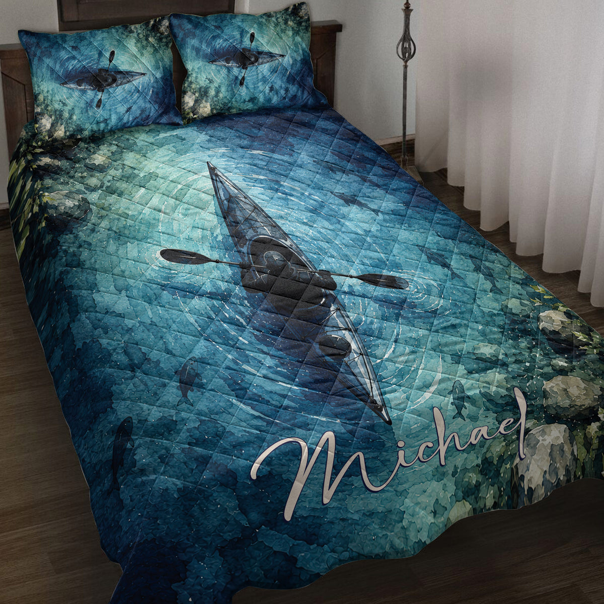 Blue kayak quilt blanket displayed on a bed with paddlers, fish, rippling water, and coastal artwork