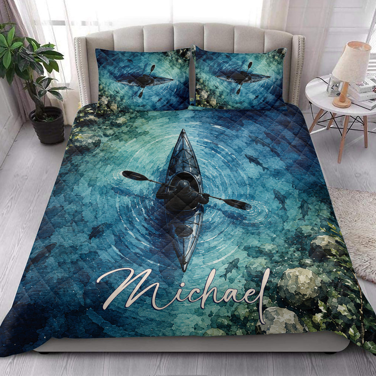 Kayak quilt blanket styled on a bedroom bed with vivid blue water, fish, and paddling artwork