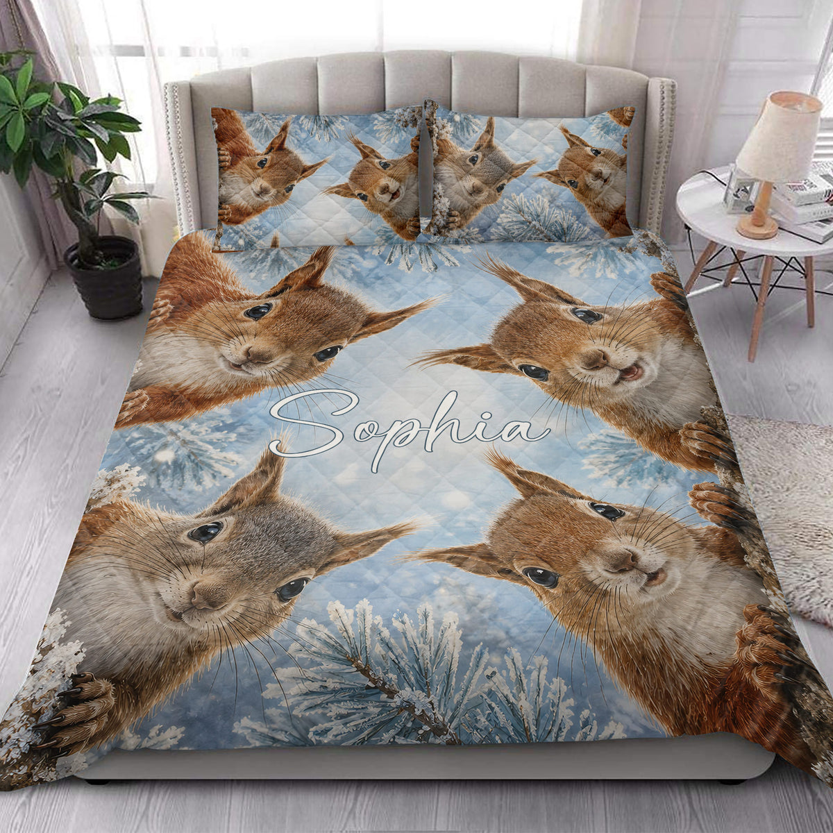 Squirrel quilt blanket styled on a bedroom bed with blue woodland branches and playful squirrel artwork