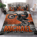 Motocross quilt bedding styled on a bedroom bed with bold orange and black rider artwork