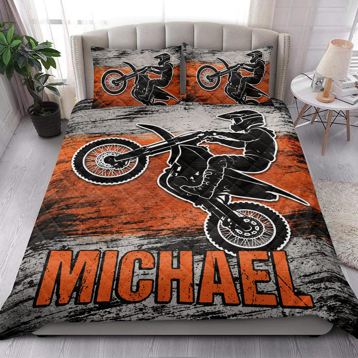 Motocross quilt bedding styled on a bedroom bed with bold orange and black rider artwork