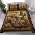 Cowgirl quilt bedding styled in a bright bedroom with Western boots, hat, cactus, and floral artwork