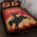 Cowgirl quilt blanket displayed on a bed with red Western artwork, rodeo silhouettes, horses, cacti, and desert scenery