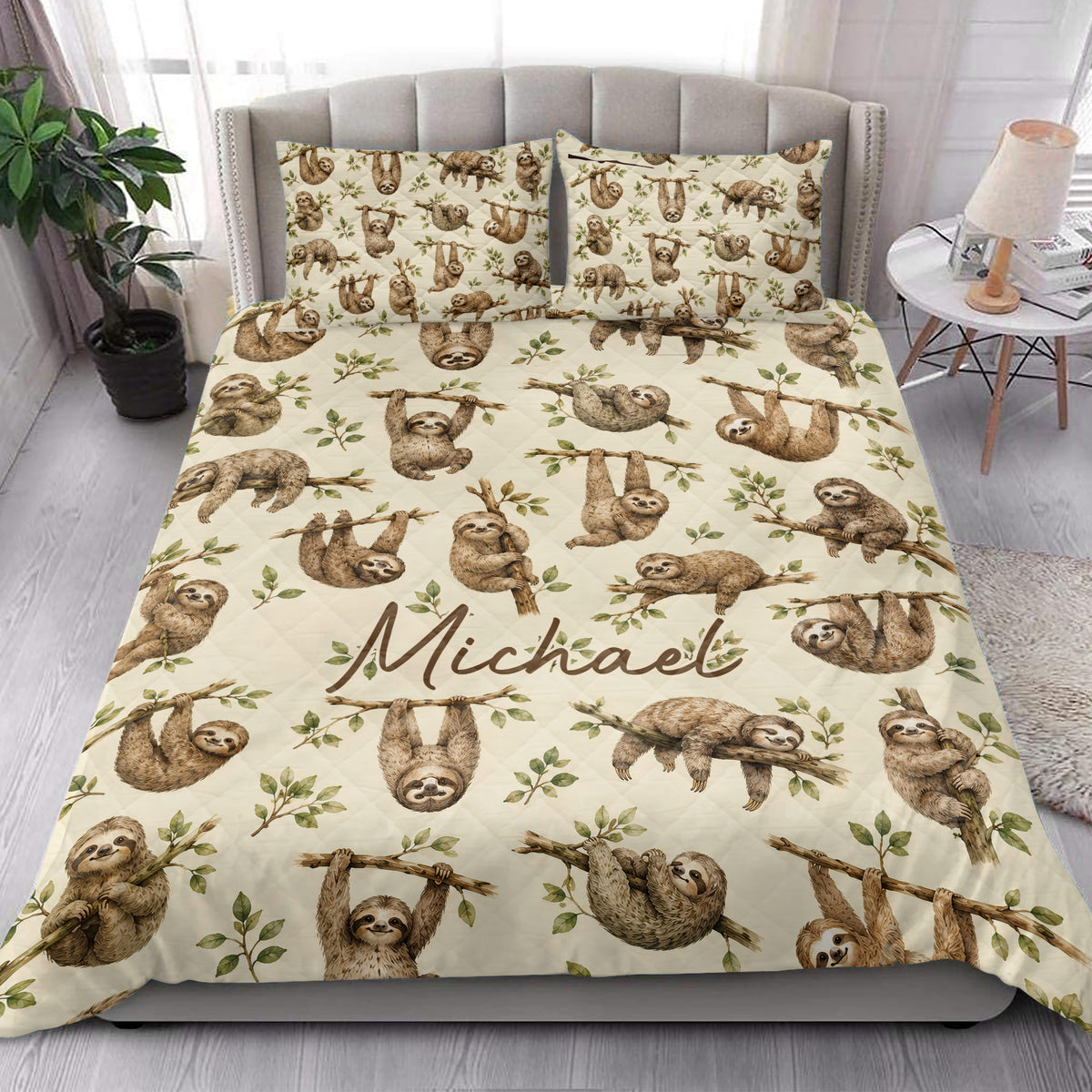Sloth quilt blanket styled in a bright bedroom with leafy branch artwork and earthy tones