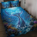 Mermaid quilt blanket displayed on a bed with an underwater coral reef, fish, and vivid blue tail artwork