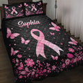 Black breast cancer quilt blanket with pink ribbons, butterflies, flowers, and heart accents on a bed