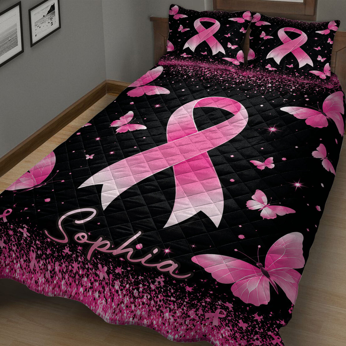 Close bedroom view of a black quilt blanket with a large pink ribbon and butterfly artwork