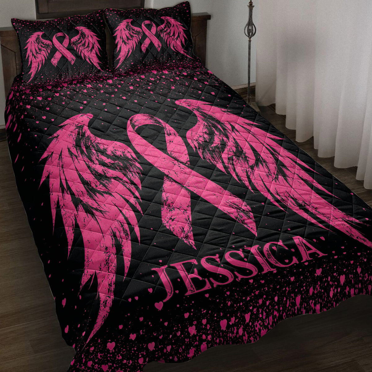 Black and pink breast cancer quilt blanket displayed on a bedroom bed with ribbon and wing artwork