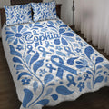 Blue diabetes awareness ribbon quilt blanket with floral artwork styled on a bedroom bed