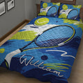 Close bedroom view of a blue tennis quilt blanket featuring a large racket and tennis balls