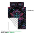 Dragonfly quilt blanket displaying a printed black floral front and white quilted backing