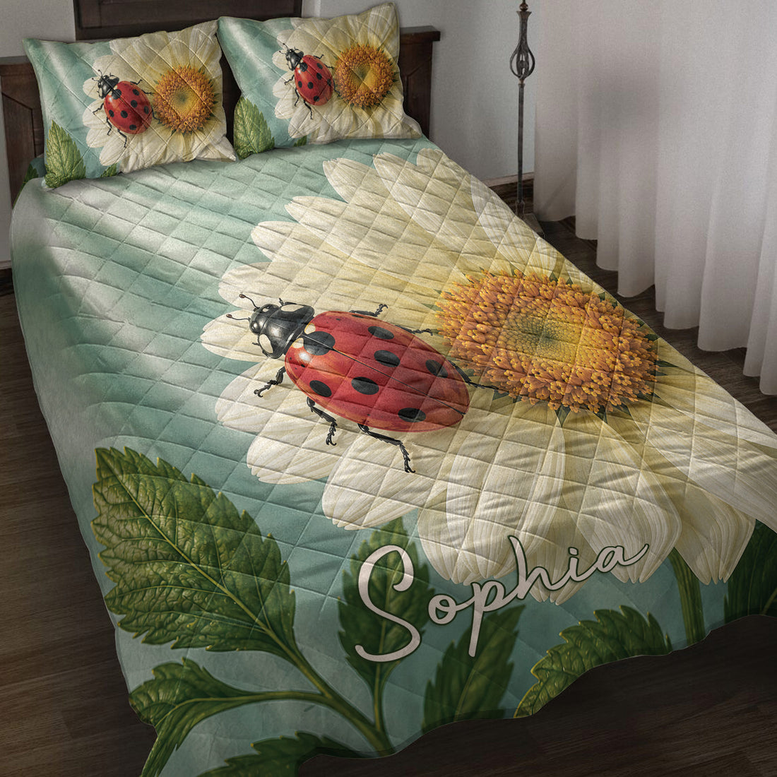 Ladybug quilt blanket displayed on a bed with daisies, green leaves, and soft teal botanical tones