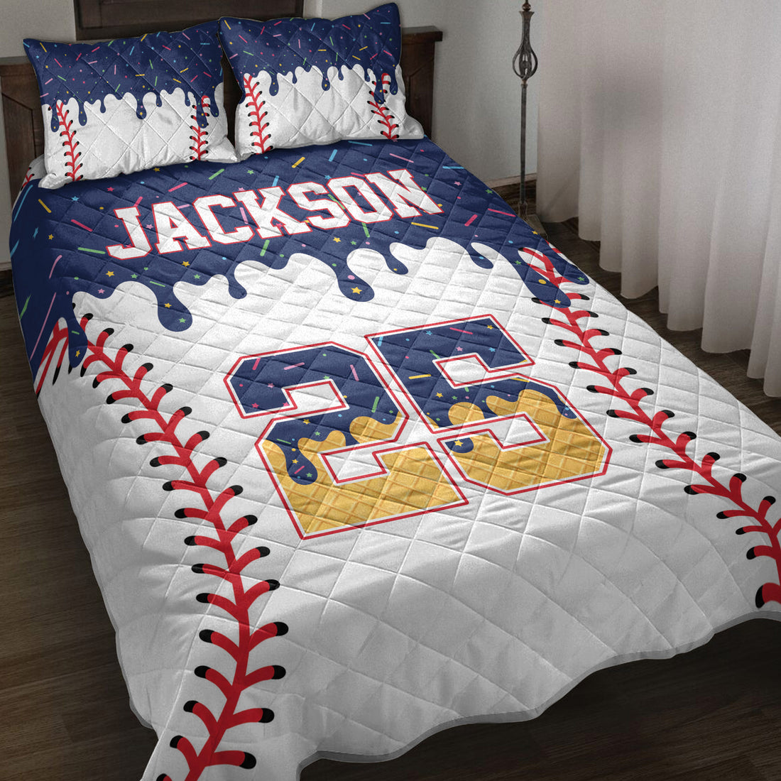 Baseball quilt blanket displayed on a bed with red stitching graphics, colorful accents, and bold sports artwork