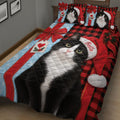 Close view of a tuxedo cat Christmas quilt blanket with holiday lights, decorated tree, gifts, and red winter motifs