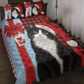 Tuxedo cat Christmas quilt blanket displayed on a bed with a decorated tree, gifts, lights, and snowflake accents