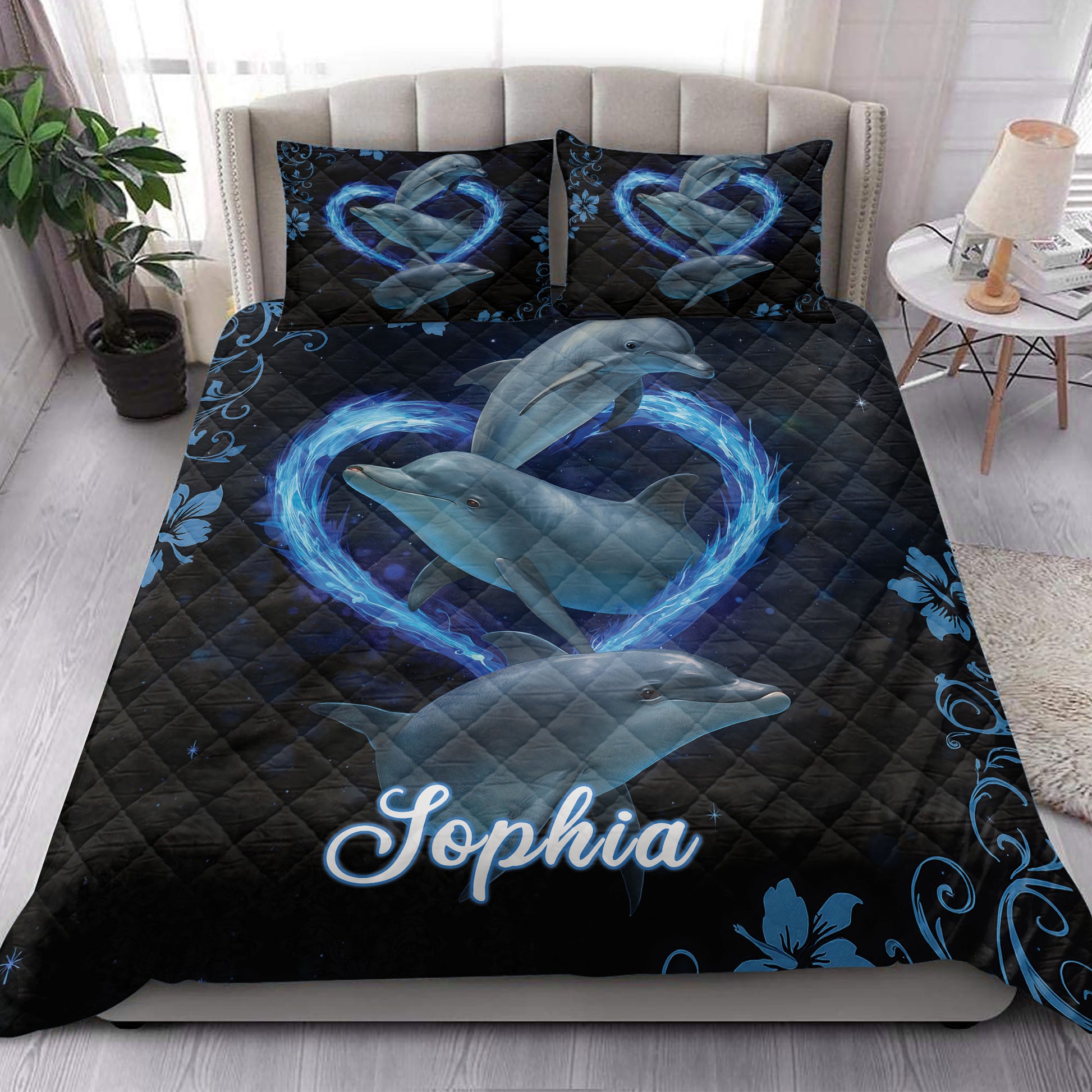 Dolphin quilt bedding styled on a bedroom bed with blue wave hearts and dark ocean artwork