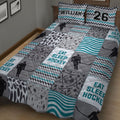 Hockey quilt blanket displayed on a bed with hockey player silhouettes, puck patterns, stars, and teal waves