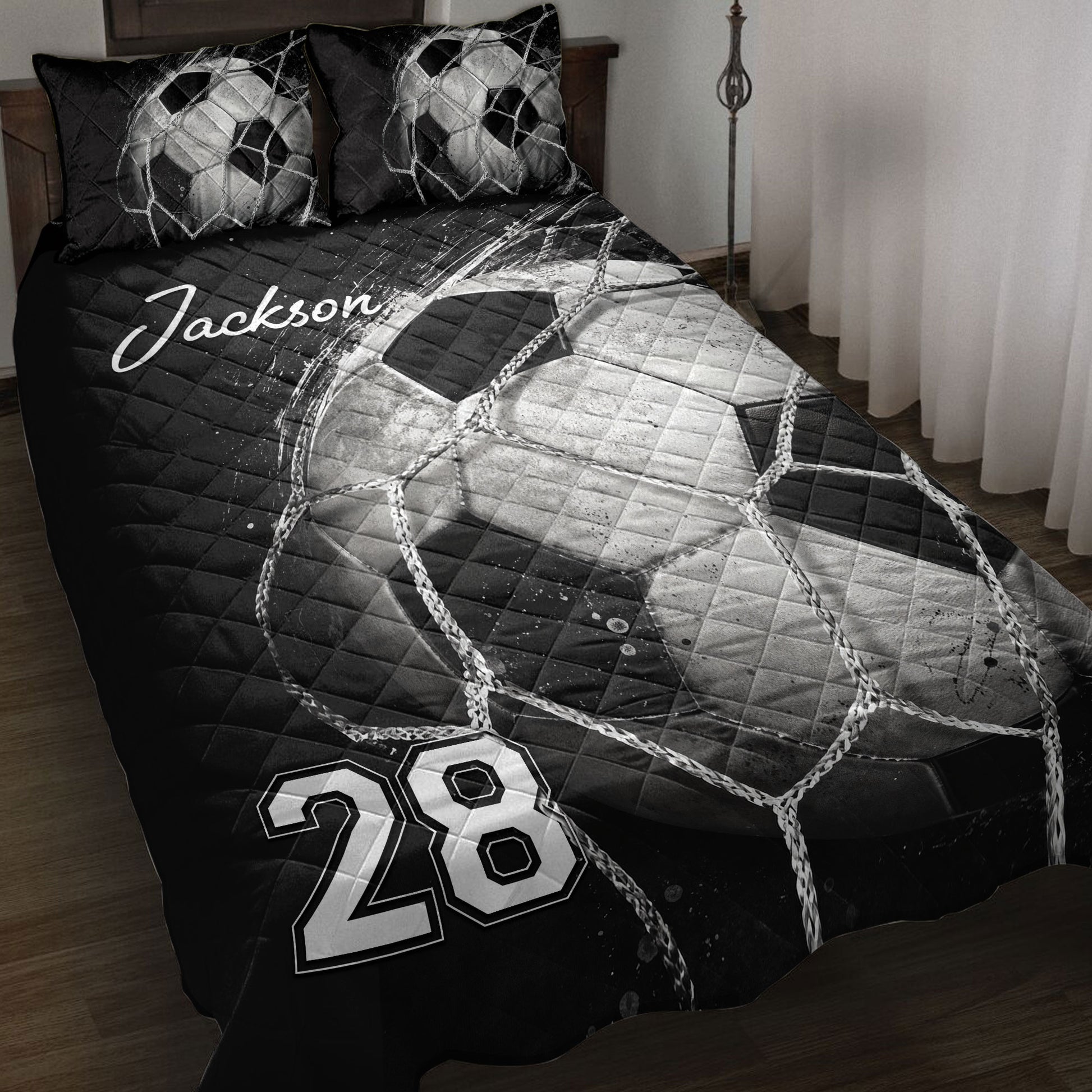 Black and white soccer quilt blanket displayed on a bed with soccer ball net artwork
