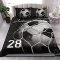 Soccer quilt blanket styled on a bedroom bed with dramatic monochrome ball artwork