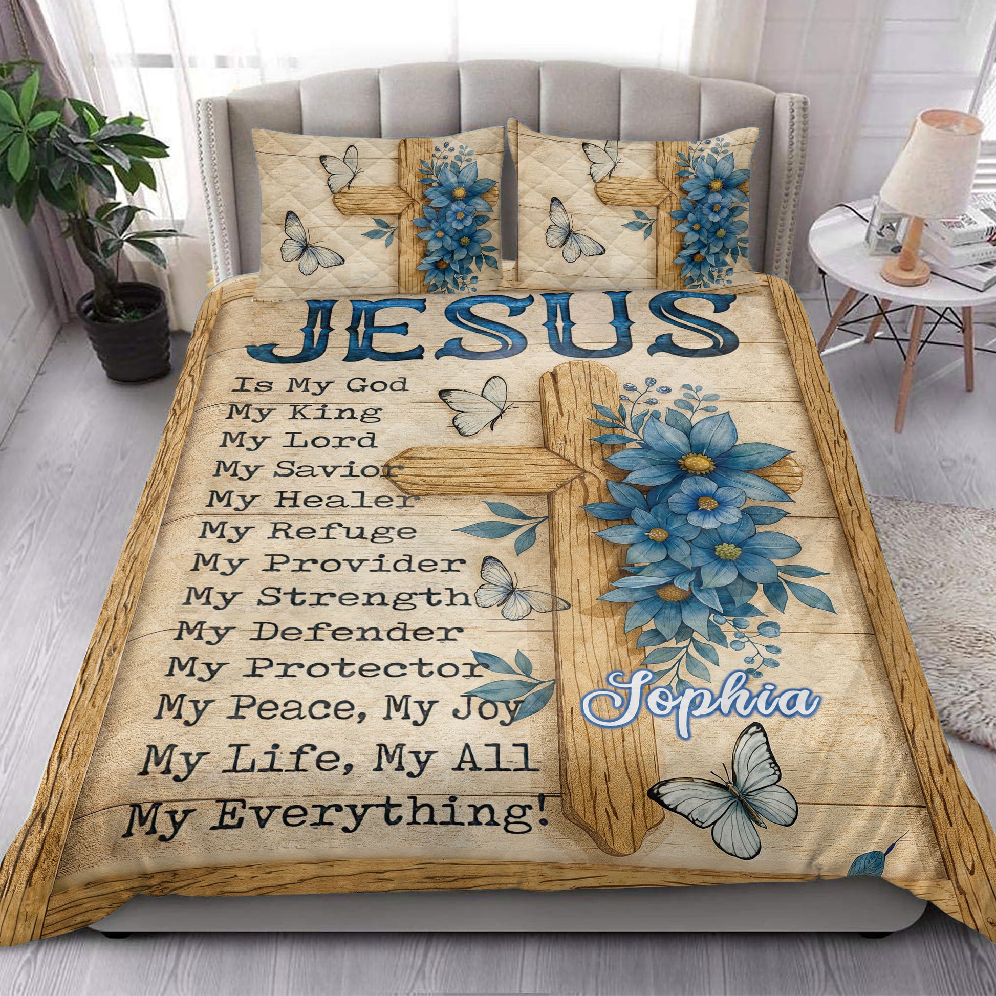 Christian quilt blanket styled in a bright bedroom with blue flowers, butterflies, cross artwork, and faith wording