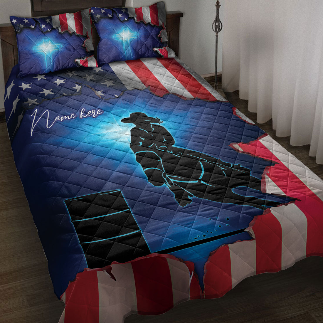 Barrel racing quilt blanket displayed on a bed with cowgirl rider silhouette, barrel artwork, and patriotic flag design