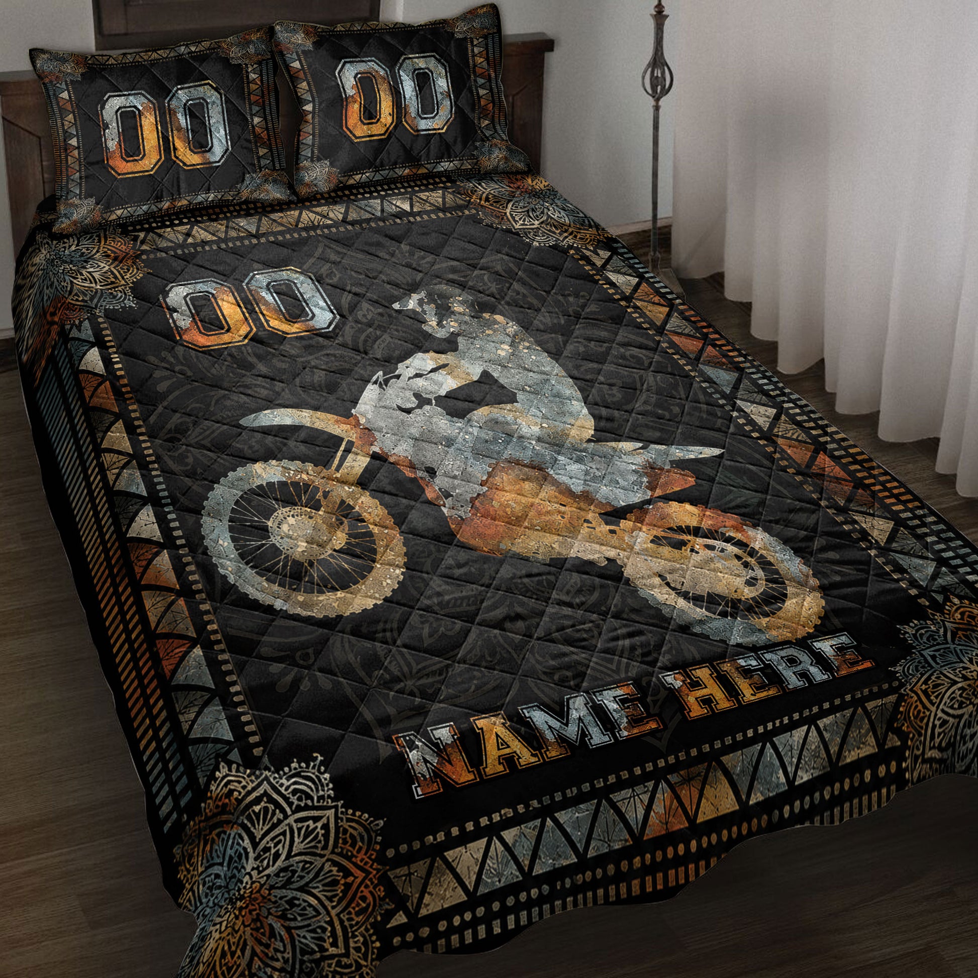 Motocross quilt blanket displayed on a bed with dirt bike rider artwork in black, orange, and silver