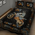 Close view of motocross quilt bedding with rider, dirt bike wheels, and black orange geometric artwork