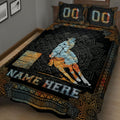Close view of a black and gold barrel racing quilt blanket featuring a horse, rider, barrels, and decorative border