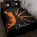 Black and orange basketball quilt blanket styled on a bed with basketball artwork and matching pillows