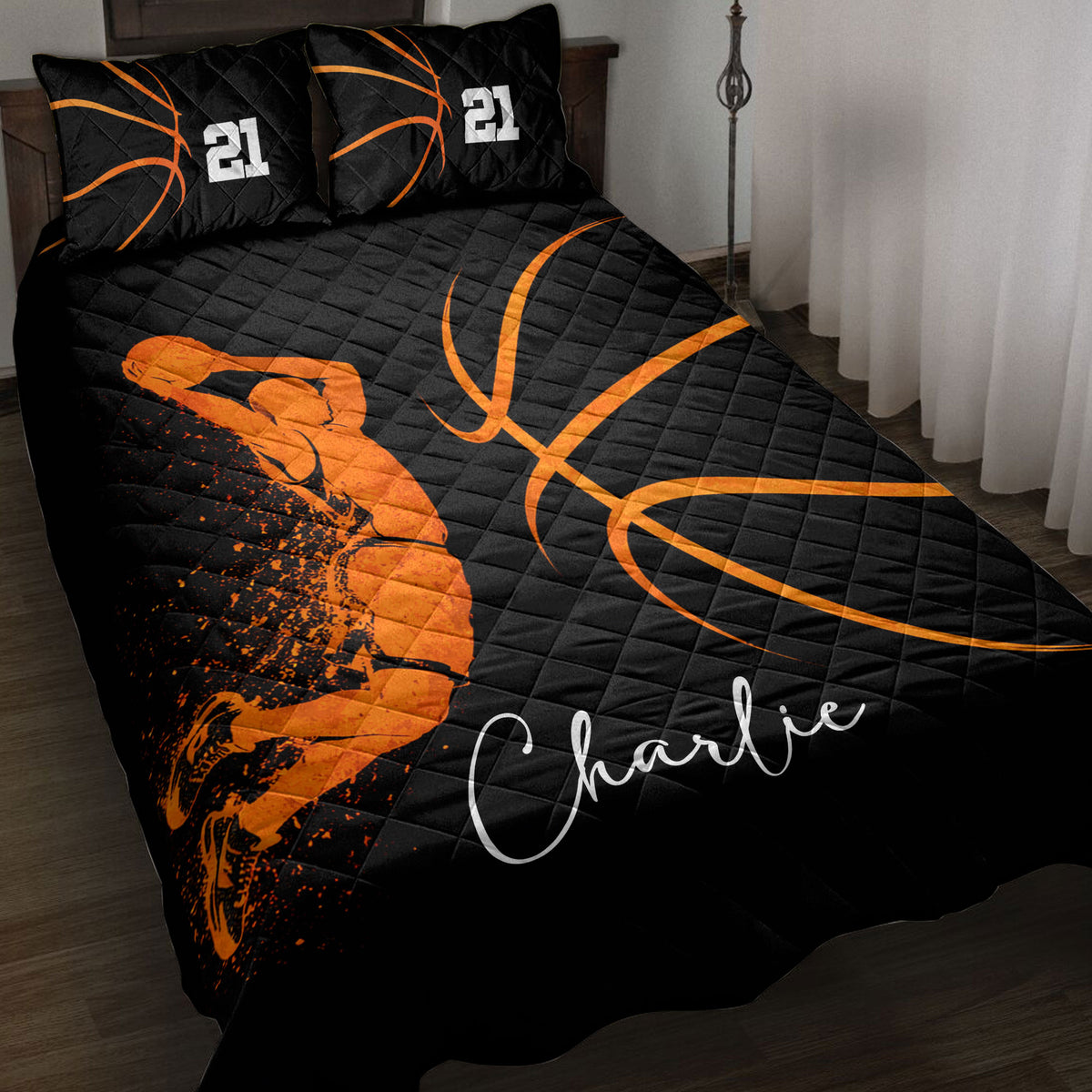 Black and orange basketball quilt blanket styled on a bed with basketball artwork and matching pillows