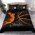 Black and orange basketball quilt blanket displayed in a bright bedroom with basketball artwork