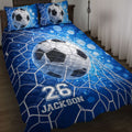 Blue soccer quilt blanket displayed on a bed with soccer ball artwork and dark goal net graphics
