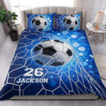 Blue soccer quilt blanket styled in a bright bedroom with large soccer ball artwork