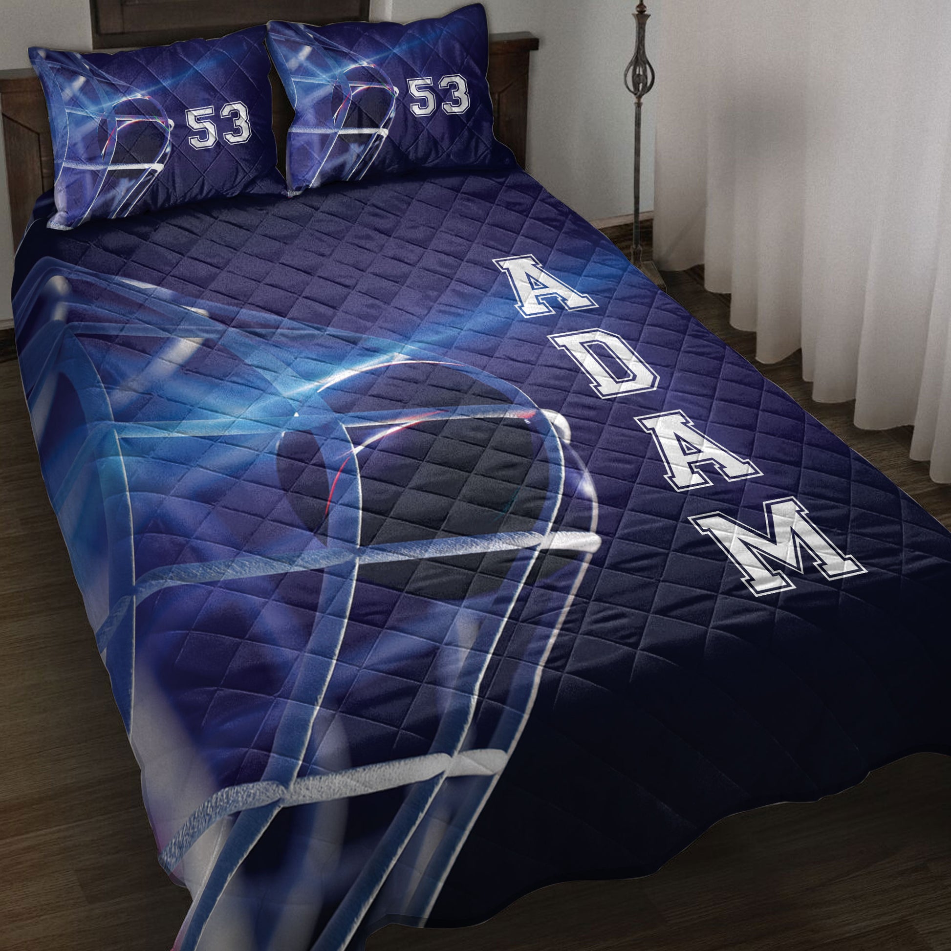 Blue hockey quilt blanket styled on a bed with helmet artwork, bold rink-inspired graphics, and pillow options