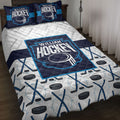 Hockey quilt blanket displayed on a bed with navy and cyan graphics, hockey sticks, pucks, and matching pillows