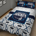 Close bedroom view of a hockey quilt blanket featuring a central hockey emblem and repeating rink-inspired artwork