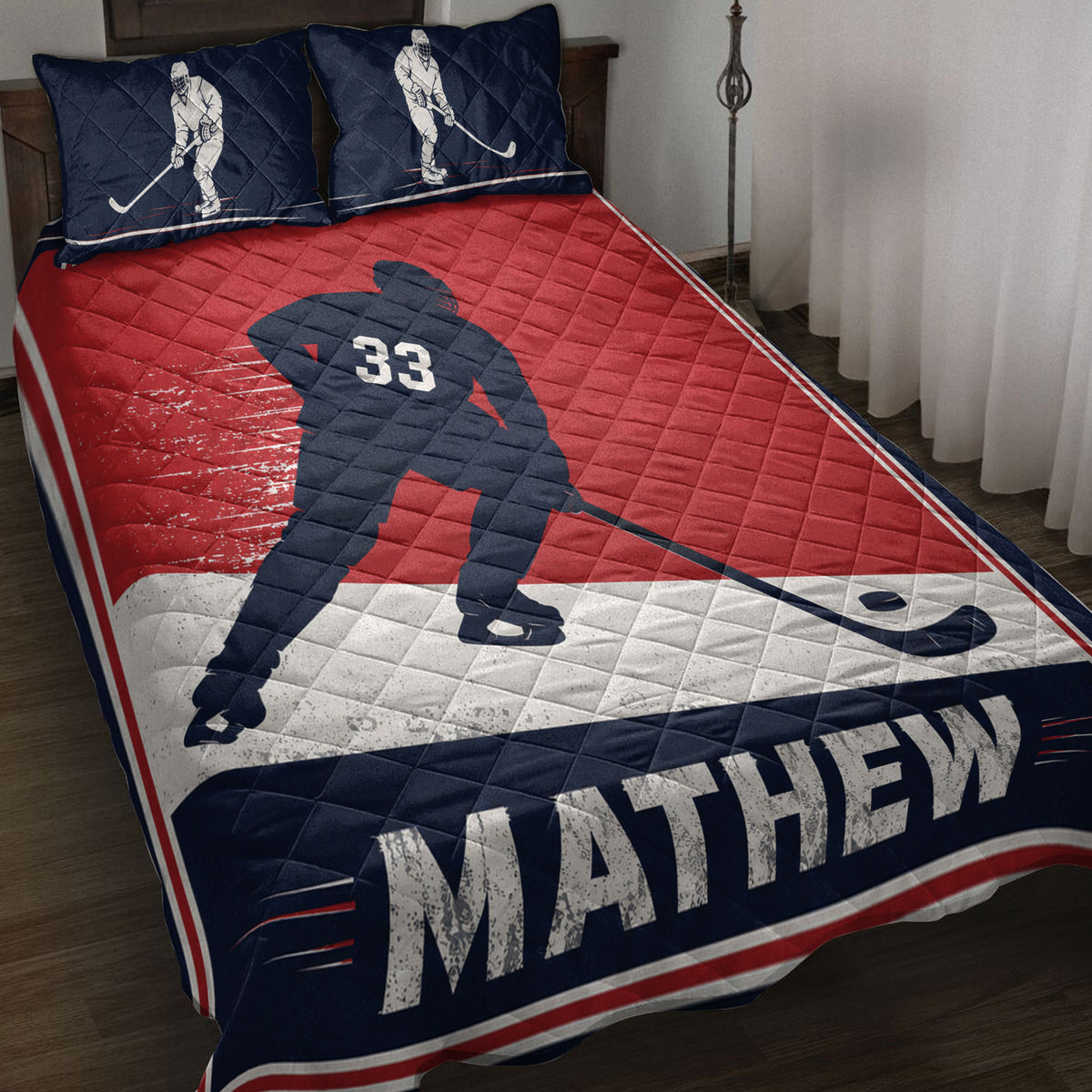 Red, navy, and white hockey quilt blanket displayed on a bed with skating player artwork and hockey stick details