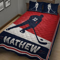 Close bedroom view of a hockey quilt blanket featuring a skating player, hockey stick, puck, and bold sports colors