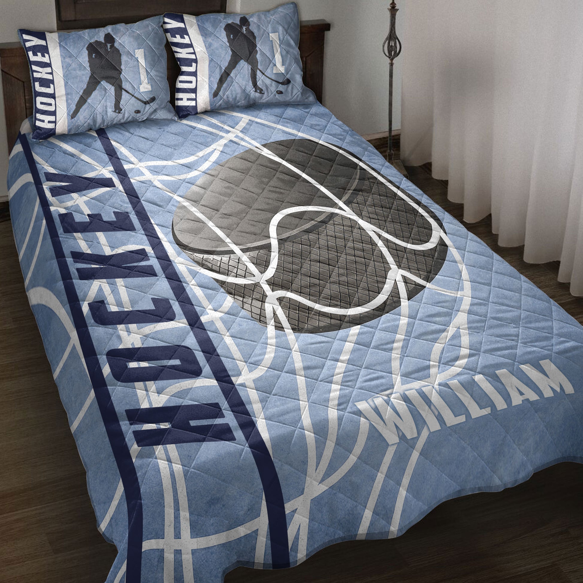 Hockey quilt blanket styled on a bed with blue rink-inspired artwork, hockey sticks, pucks, and player silhouettes