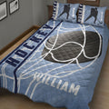 Close bedroom view of a blue hockey quilt blanket featuring oversized hockey equipment graphics and player silhouettes