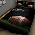 Close bedroom view of a black football quilt blanket with large football artwork and green grass details