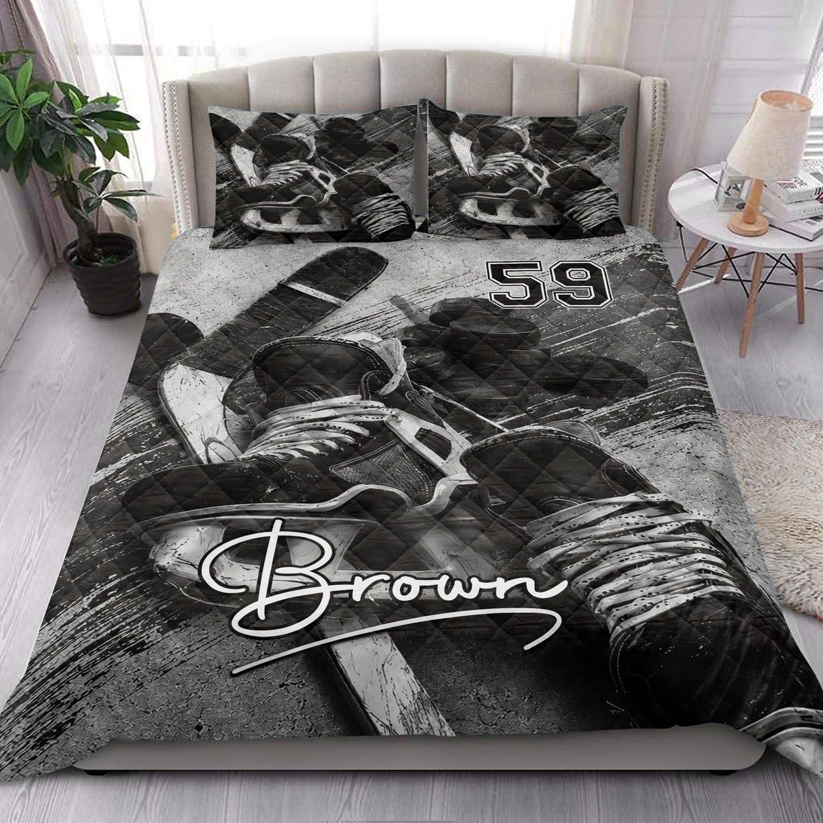 Hockey quilt blanket styled in a bedroom with dramatic black and white hockey equipment artwork