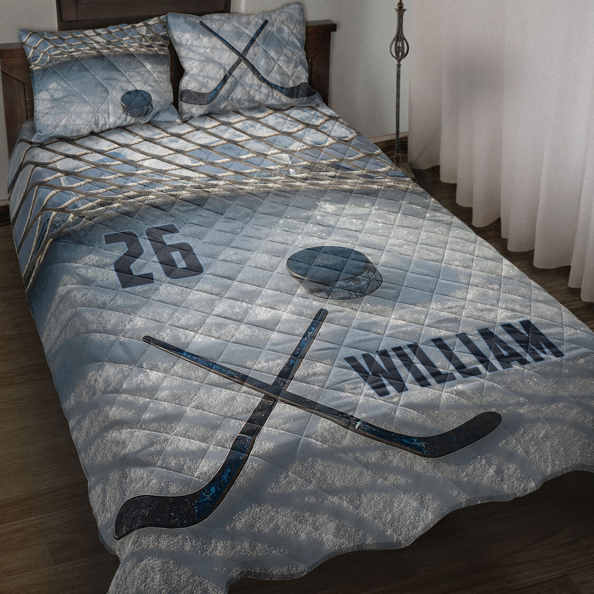 Blue hockey quilt blanket displayed on a bed with crossed sticks, puck, net pattern, and sports artwork