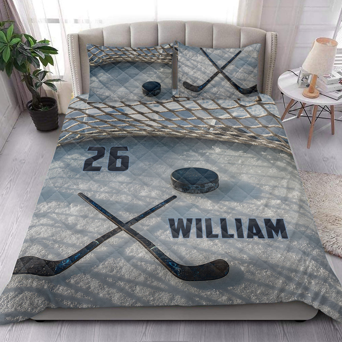 Hockey quilt blanket styled on a bedroom bed with crossed hockey sticks, puck, and blue net-inspired design
