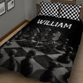 Angled bedroom view of a black chess quilt blanket with chess pieces and checkerboard details