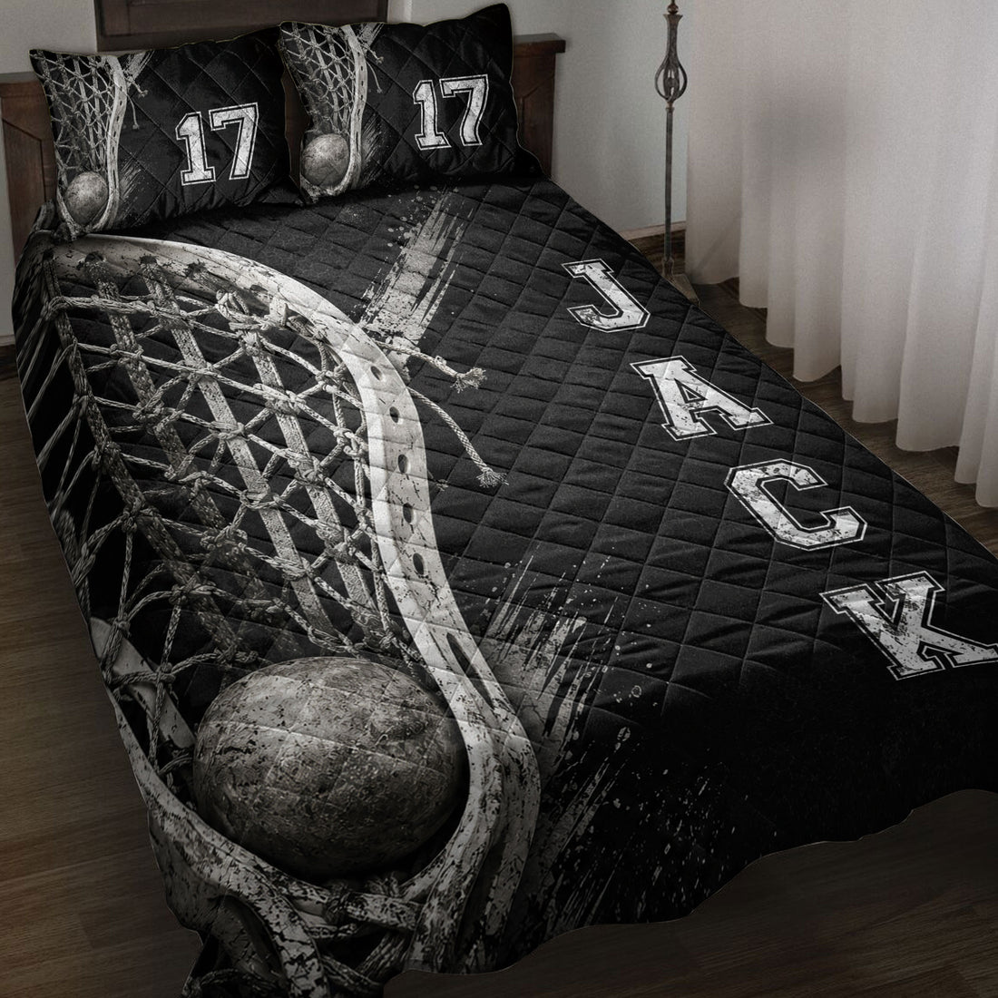 Black lacrosse quilt blanket displayed on a bed with stick, net, ball, and bold athletic lettering artwork
