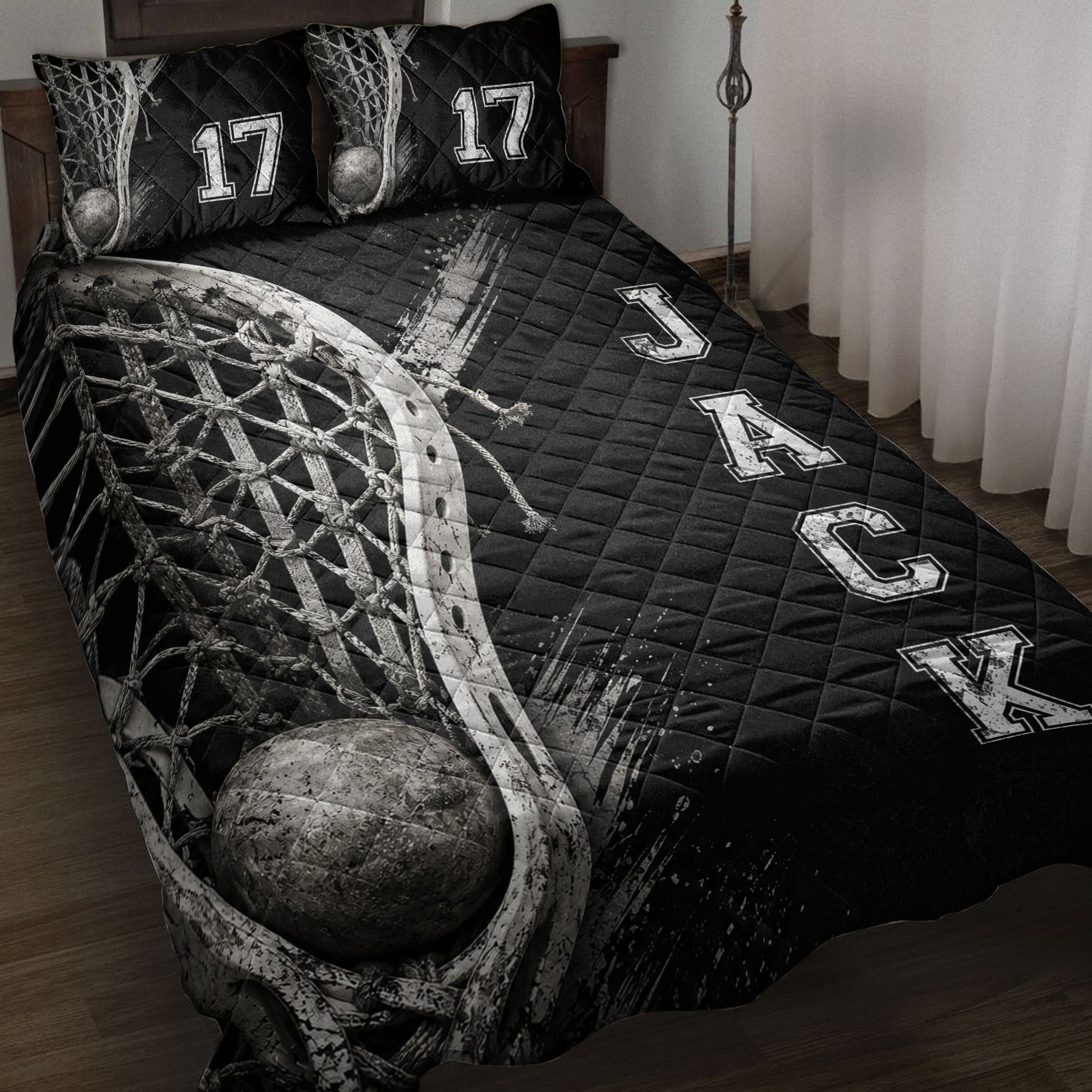 Black lacrosse quilt blanket displayed on a bed with stick, net, ball, and bold athletic lettering artwork