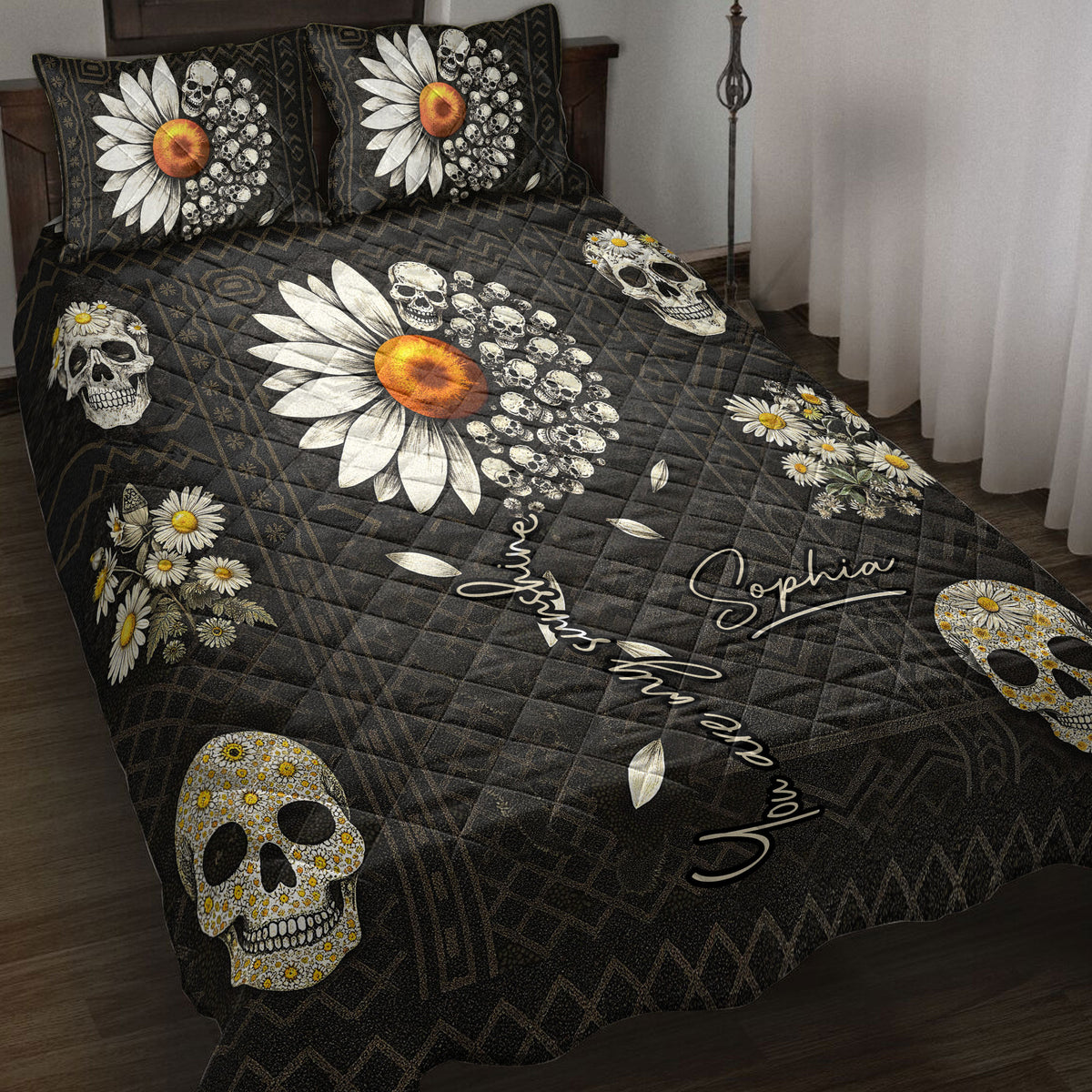 Skull quilt blanket displayed on a bed with daisies, orange flowers, geometric patterns, and black gothic artwork